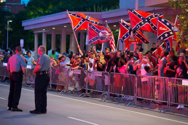People wave Confederate flags outside the hotel that President Barack Obama is staying the night, on Wednesday, July 15, 2015, in Oklahoma City.  Obama is traveling in Oklahoma to visit El Reno Federal Correctional Institution. (AP Photo/Evan Vucci)
